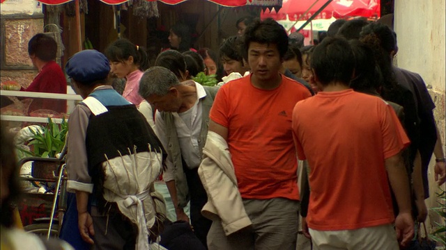 在中国云南丽江中意户外市场，成群的人走过狭窄的通道视频素材