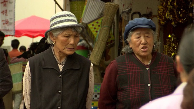 中国云南丽江，两名老年妇女在街上聊天，肩并肩走过中义露天市场视频素材