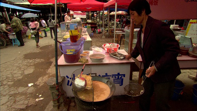 中国云南丽江，市场小贩用油煮饺子视频素材