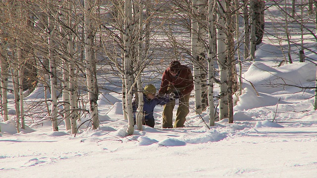 一对穿着雪地鞋穿过树林的夫妇/凯彻姆，美国爱达荷州视频素材