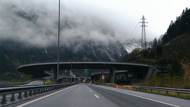 汽车的观点接近高山隧道/驾驶通过昏暗的隧道/出现在卡车后面的另一边/通过桥下和天桥/瑞士视频素材