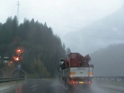 2002年宽镜头汽车视角驾驶通过隧道/在雨中从隧道后面的卡车出现/进入隧道/欧洲视频素材