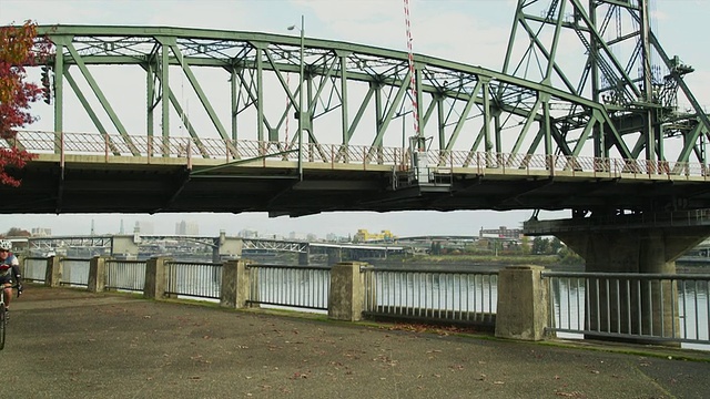 WS PAN Man骑着自行车，背景是Hawthorne bridge /波特兰，俄勒冈，美国视频素材