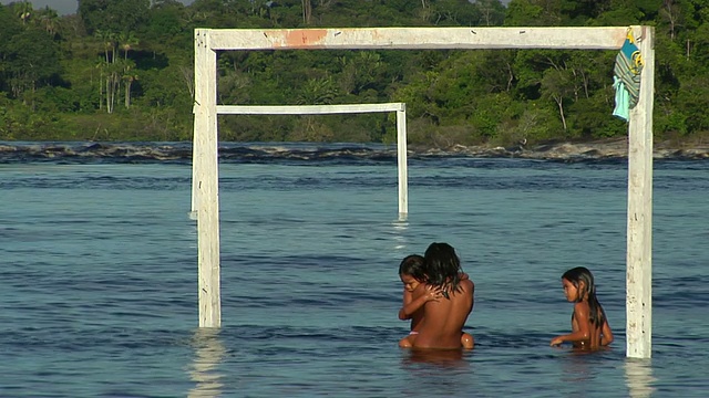 SLO MO WS后视图三个女孩在足球门柱在夏季洪水/ Sao Gabriel da Cachoeira，亚马孙，巴西视频素材