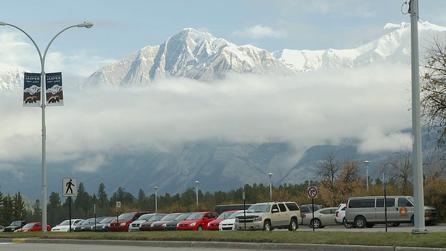 停车场上的一排汽车，背景是白雪覆盖的山脉和云彩/加拿大阿尔伯塔省的贾斯珀视频素材