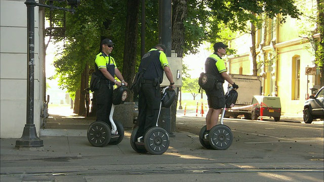 WS TS ZI三名运输安全人员在美国俄勒冈州波特兰的人行道上骑着segway视频素材