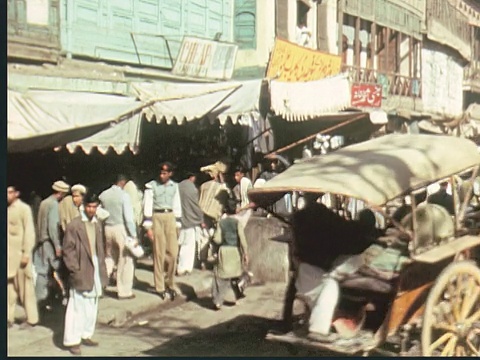 1960蒙太奇繁忙的城市街道市场与马车。人头上顶着大篮子。有人在街上卖地毯。有面料/巴基斯坦的商店视频素材