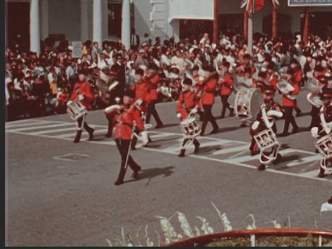 1966蒙太奇狗躺在游行队伍前的街道上。英国的军乐队。花节。花车上的花后在挥手。许多花车覆盖着花/汉密尔顿，百慕大视频素材