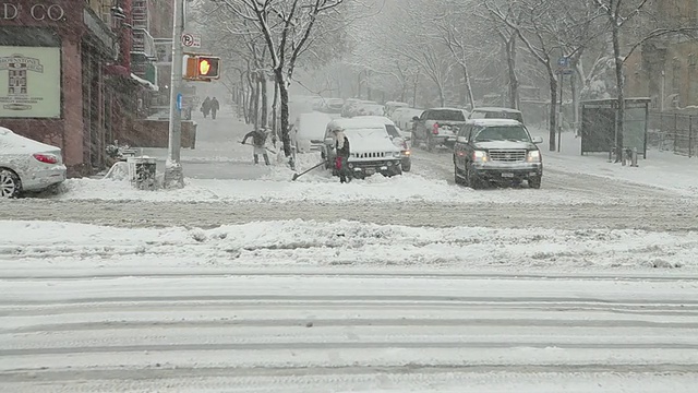 美国纽约，汽车在下雪的街道上行驶，人们在铲雪视频素材