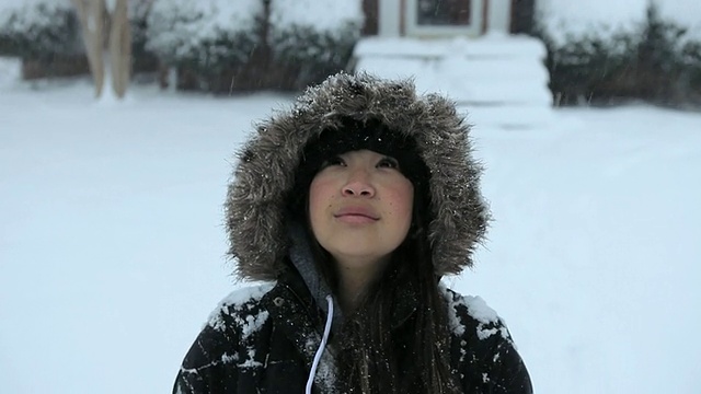 年轻女子在房子前仰望着飘落的雪/里士满，弗吉尼亚州，美国视频素材