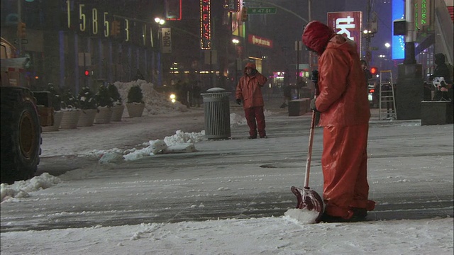 WS PAN Man在麦迪逊大道在下雪的夜晚铲人行道/纽约，美国视频素材