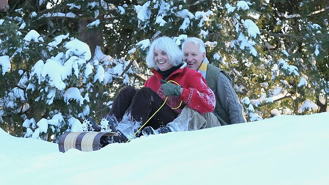 好玩的婴儿潮夫妇在美国弗吉尼亚州里士满雪地上骑着雪橇下山视频素材