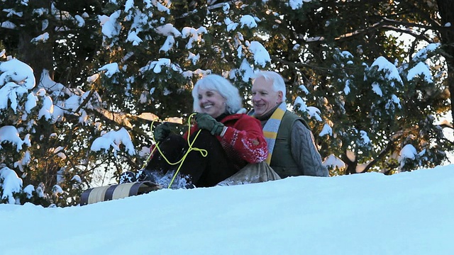 好玩的婴儿潮夫妇在美国弗吉尼亚州里士满雪地上骑着雪橇下山视频素材