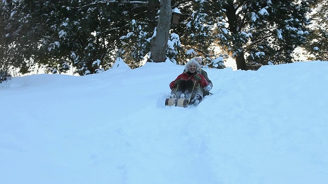 好玩的婴儿潮夫妇在美国弗吉尼亚州里士满雪地上骑着雪橇下山视频素材