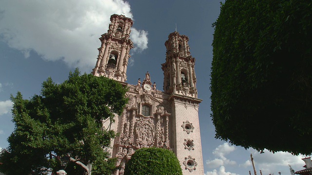 WS LA Santa Prisca Church against sky with white clouds, trees in foreground /塔斯科，格雷罗，墨西哥视频素材