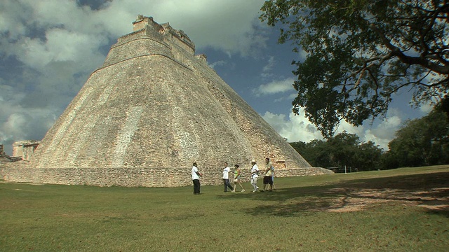 墨西哥尤卡坦半岛前哥伦布时期的玛雅文明废墟城市Uxmal，一群游客在阿迪维诺(魔术师金字塔)视频素材