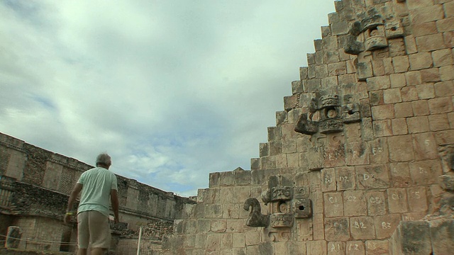 在墨西哥尤卡坦半岛前哥伦布遗址玛雅文明城市Uxmal，一名正在攀登魔术师金字塔的男子视频素材