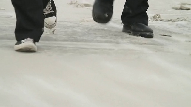 SLO MO CU四名穿着黑色衣服的男子走过海滩/杰克逊维尔，美国佛罗里达州视频素材