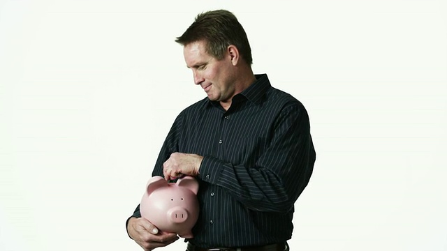 MS Portrait of man holding piggy bank against white background /奥勒姆，犹他州，美国视频素材