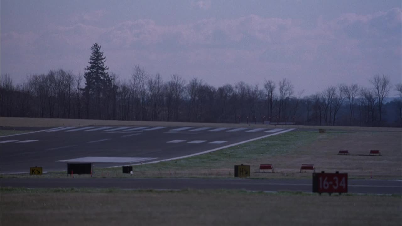 西北航空公司的小四引擎商用客机在小机场跑道上降落的跟踪镜头。背景中机场周围的光秃秃的树木。飞机从左边飞过。视频素材