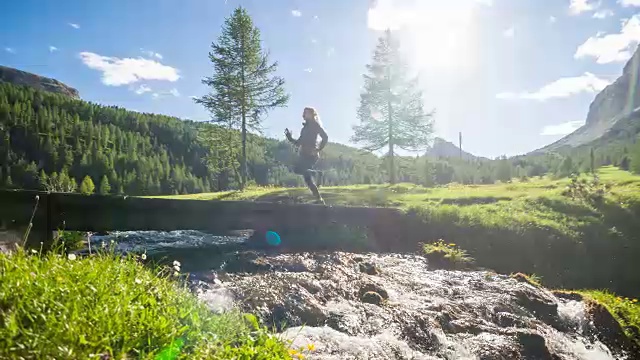 健康导向的年轻运动健身妇女在一个绿色景观旁边的水的木制路径上跑步视频素材