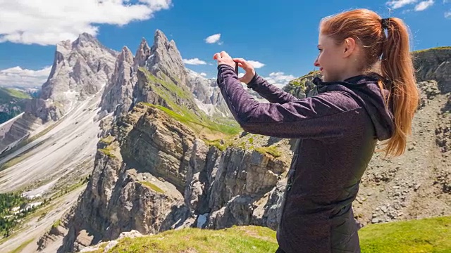 快乐的女性游客探索山坡，站在山顶上，用智能手机拍摄山景在一个美丽的阳光明媚的日子视频素材