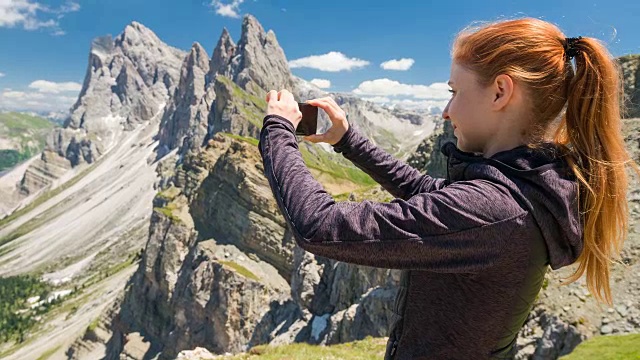 一名女性徒步旅行者在山顶用智能手机拍照视频素材