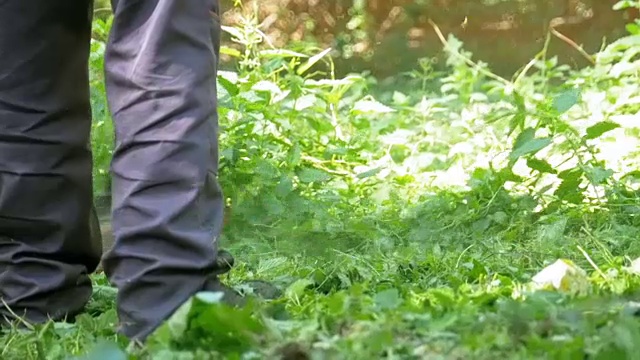 在慢镜头中，一名男子用便携式割草机割草视频素材