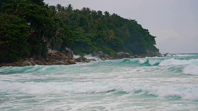 慢镜头，海浪和浪花在暴风雨前慢慢地拍打着岩石和海滩视频素材