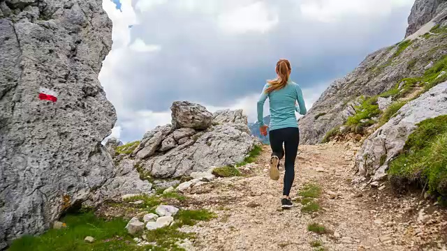 女跑步者在山区的岩石小径上跑步视频素材