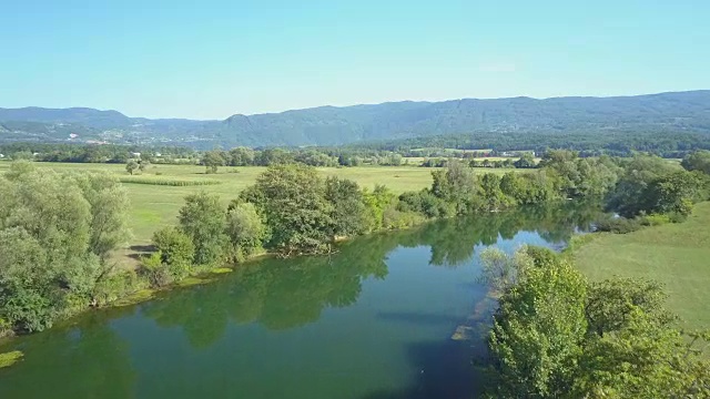 航拍:飞下一条宁静的深蓝色河流，流经乡村。视频素材