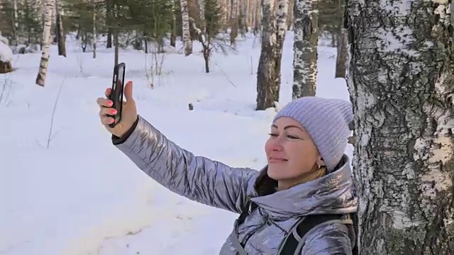 一个女人走在树林里。旅行者在森林里用手机拍照。女孩会自拍，用智能手机交流。美丽多汁的日落时分。视频素材