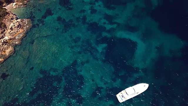 一艘游艇的鸟瞰图在一个绿宝石和透明的地中海上。意大利撒丁岛翡翠海岸(翡翠海岸)。视频素材