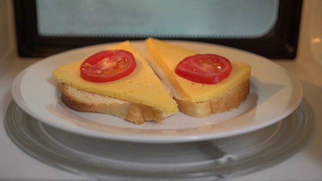 用微波炉烹饪芝士三明治。装有三明治的盘子在烤箱里旋转视频素材