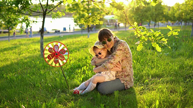 母亲和女儿愉快地花时间一起在草地上玩日落。视频素材