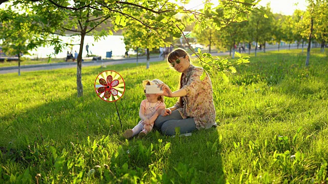 母亲和女儿愉快地花时间一起在草地上玩日落。视频素材