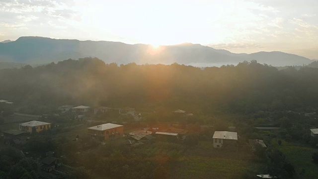 航拍的乡村村庄和高加索山脉在夏天的早晨，日出在旷野。无人机飞越云雾。格鲁吉亚。Mestia。高加索山脉视频下载