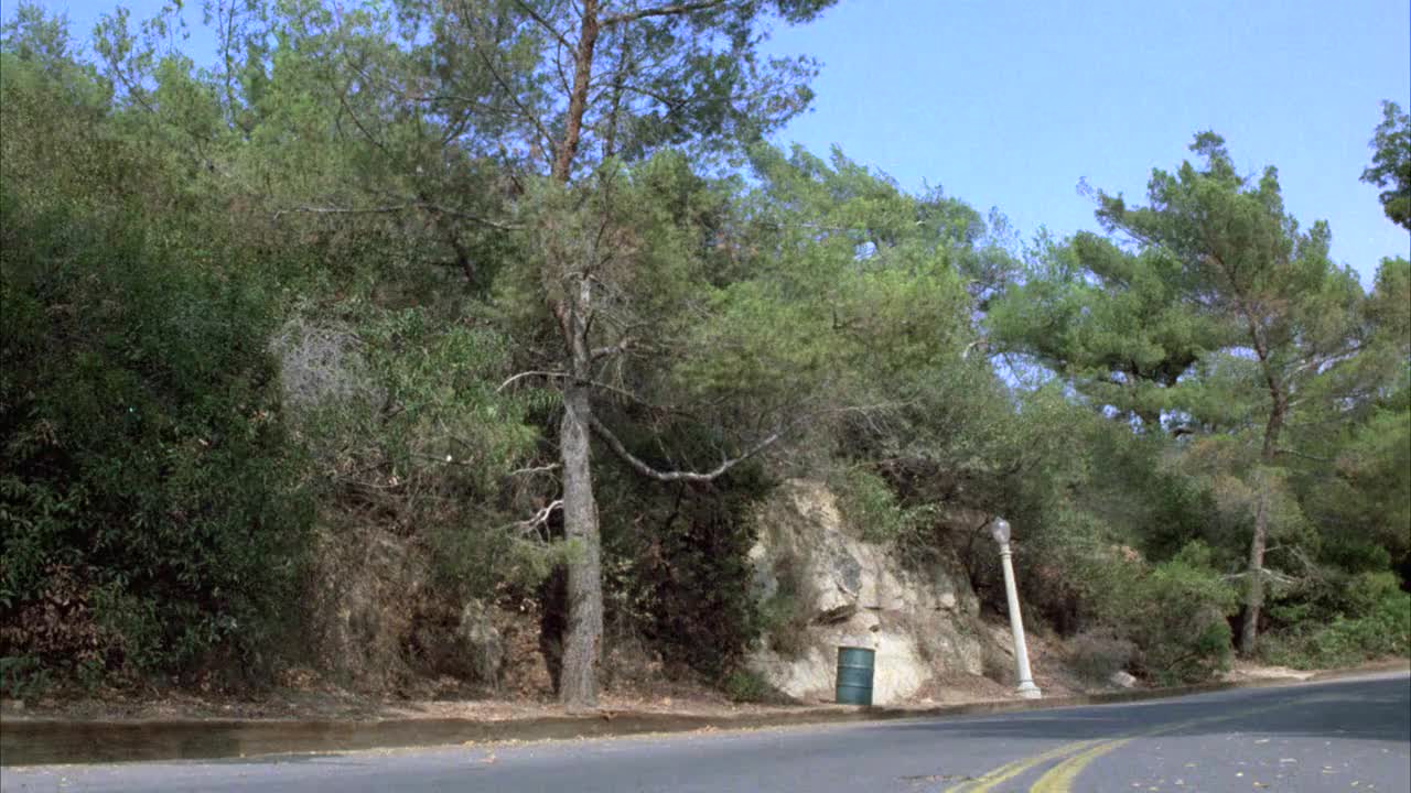 宽阔的角度，警车追逐着一辆保时捷汽车在向上的道路上走向格里菲斯公园。树。可能是蜿蜒的山路。视频素材