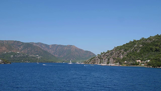 海的景观，美丽的海岸与游艇的背景在绿色的山在夏季视频素材