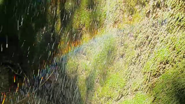 慢镜头，瀑布在山上高速卷。特写的春天的水滴下落和溅在绿色的苔藓视频素材