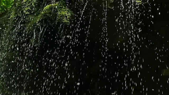 慢镜头，瀑布在山上高速卷。特写的春天的水滴下落和溅在绿色的苔藓视频素材