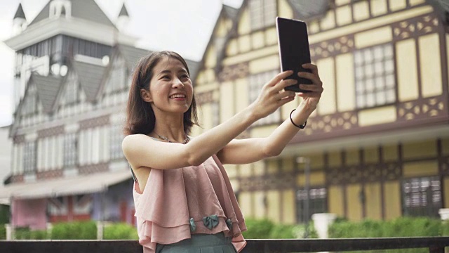 漂亮的年轻亚洲女性游客自拍，并与智能手机谈论城市背景，旅游和科技概念视频素材