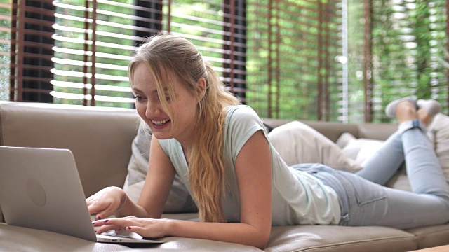 女子躺下使用笔记本电脑在沙发上在线聊天视频素材