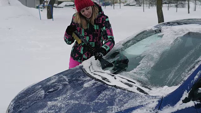 女人用刮刀清理挡风玻璃上的雪和冰视频素材