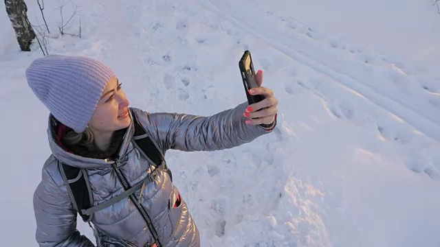 一个女人走在树林里。旅行者在森林里用手机拍照。女孩会自拍，用智能手机交流。美丽多汁的日落时分。视频素材