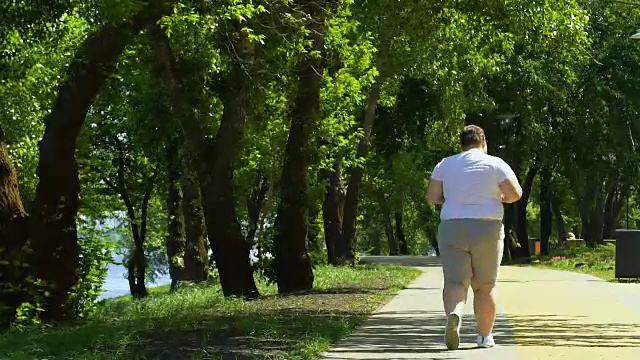 肥胖男性在公园慢跑，试图减肥，运动和健康的生活方式视频素材