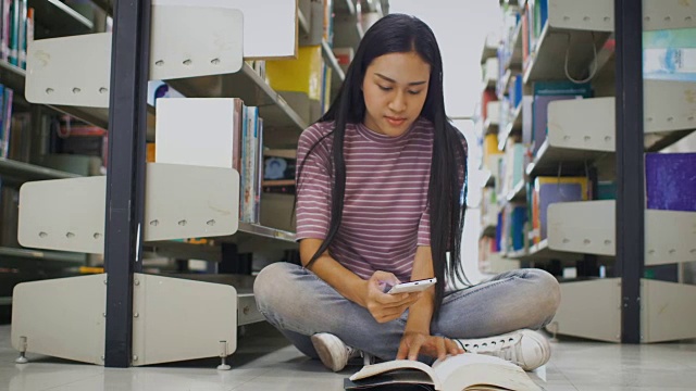 年轻的亚洲女学生在大学图书馆看书和拍照，教育和学校理念视频素材