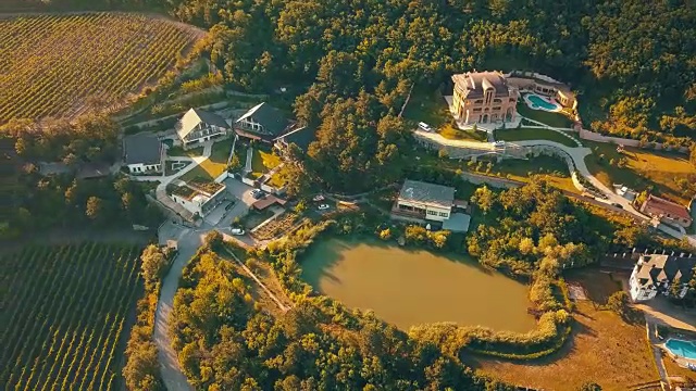 在梦幻般的阳光下，鸟瞰豪华的夏季别墅公寓建筑，泳池靠近山湖视频素材