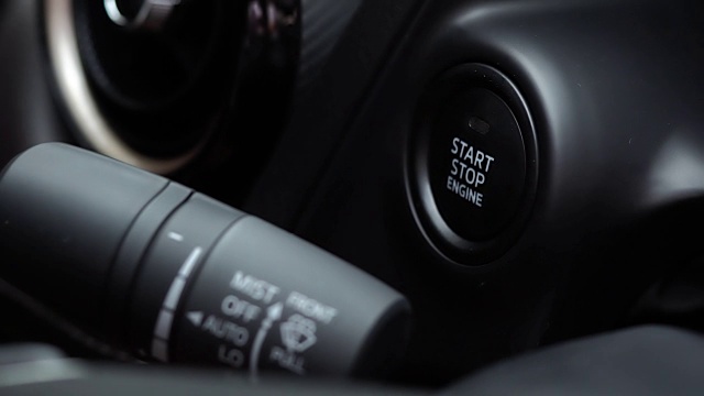 在现代自动汽车上，男性手指的闭合按下发动机启动和停止按钮视频素材
