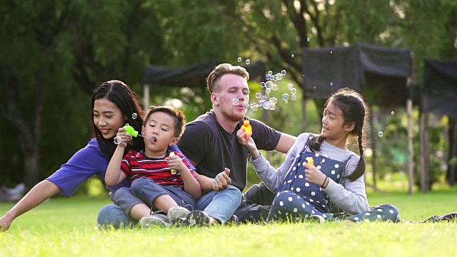 一家人带着孩子在户外吹肥皂泡。周末活动的概念。视频素材